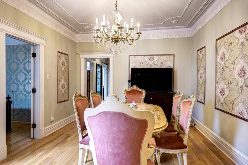 Salle à manger avec moulures et lustre, ouverte sur les autres pièces